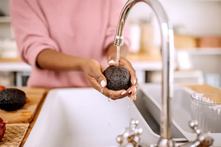 woman washes avocado in sink