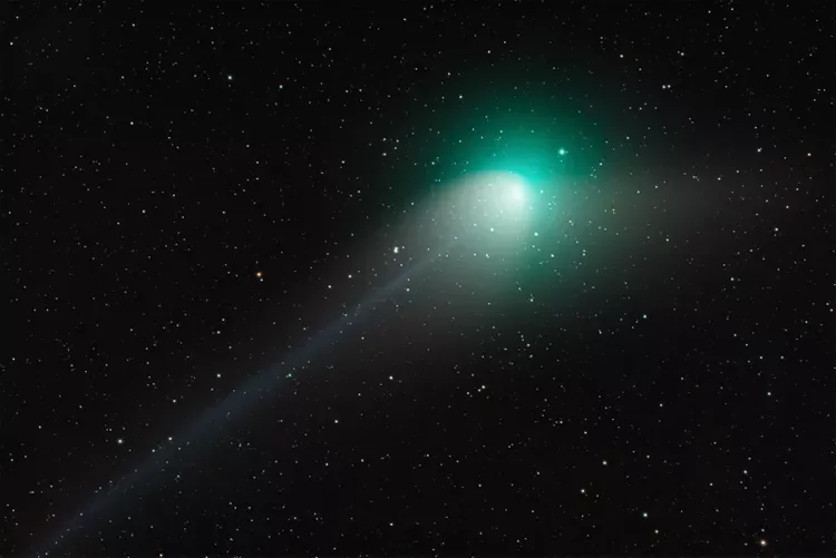 THe dark night sky is brighten by a flash of green comet